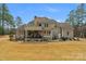 Spacious home exterior with a stone chimney, covered patio, and well-maintained lawn at 4009 Beechwood Spring Ln, Belmont, NC 28012