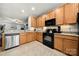 Modern kitchen features wood cabinets, black appliances, and stone countertops for a sophisticated culinary space at 6936 Colonial Garden Dr, Huntersville, NC 28078