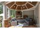 Inviting outdoor patio with comfortable seating, a stone fireplace, wood ceiling, and views of lush greenery at 7913 Buena Vista Dr, Denver, NC 28037