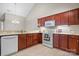 Well-lit kitchen featuring wooden cabinets, white appliances, and a sink beneath a modern chandelier at 824 Wynnshire Dr # D, Hickory, NC 28601