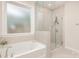 Bright bathroom featuring a soaking tub, a glass-enclosed shower, and neutral tile at 9534 Liberty Hill Dr # 196, Mint Hill, NC 28227
