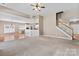 Inviting living room featuring neutral carpet, staircase, and views of the kitchen area at 1016 Filly Dr, Indian Trail, NC 28079