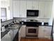Compact kitchen featuring white cabinets, stainless steel appliances, and a black countertop at 1320 Fillmore St # 419, Charlotte, NC 28203