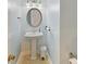 Bright half bath with a pedestal sink, oval mirror, tile flooring, and modern fixtures at 13424 Portside Ct, Charlotte, NC 28278