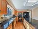 Well-lit kitchen with black appliances, black granite countertop, wood cabinets, and a stainless steel sink at 13424 Portside Ct, Charlotte, NC 28278