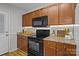 Efficient kitchen layout with black appliances, wooden cabinets, and modern lighting fixtures at 166 Chere Helen Dr, Mooresville, NC 28115