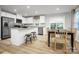 Modern kitchen and dining area with white cabinets, stainless appliances, island with stools, and wood floors at 2061 Stephens Farm Dr, China Grove, NC 28023