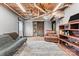 Finished basement with living area, exposed ceiling, wood-look flooring, and rustic sliding door at 24253 Old Aquadale Rd, Albemarle, NC 28001