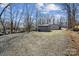 Gravel backyard with sheds and wooded perimeter; view to neighboring houses and gravel driveway at 259 Unionville Indian Trail W Rd, Indian Trail, NC 28079