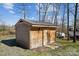 Wooden shed with a gable roof, double doors, concrete pad, lighting, and stone landscape surround at 259 Unionville Indian Trail W Rd, Indian Trail, NC 28079