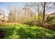 Sprawling green backyard with a wooden fence, garden beds, and mature trees at 3329 Brownes Creek Rd, Charlotte, NC 28269
