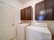 Functional laundry room featuring front load washer and dryer and upper dark cabinets at 371 Montibello Dr, Mooresville, NC 28117
