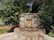 Landscaped backyard featuring a charming stone water feature amongst trees and plantings at 371 Montibello Dr, Mooresville, NC 28117