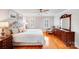 A bright bedroom with hardwood floors, a ceiling fan, two windows, and a large bed with pillows at 3716 Drayton Hall Ln, Charlotte, NC 28270