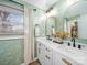 Bright bathroom featuring a double sink vanity, gold framed mirrors, and charming floral wallpaper at 404 Plaza Dr, Harrisburg, NC 28075