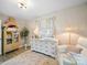 Charming Bedroom featuring a cozy armchair, dresser used as changing table and unique bookcase at 404 Plaza Dr, Harrisburg, NC 28075