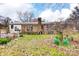 View of brick ranch home and patio in a leafy backyard, with a partial fence, a pet home and various plants at 9534 Markus Dr, Mint Hill, NC 28227