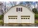 Exterior view of two-car garage with cream siding and red shutters and two window door panels at 9534 Markus Dr, Mint Hill, NC 28227