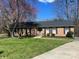 Charming brick home with a well-maintained front yard, mature trees, and a welcoming green front door at 100 Chadmore Dr, Charlotte, NC 28270