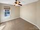 A cozy bedroom with neutral carpet, ceiling fan, and a window with natural light at 10940 Wild Dove Ln, Charlotte, NC 28277