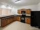 Kitchen with wood cabinets, black appliances, black countertops and tile floor at 10940 Wild Dove Ln, Charlotte, NC 28277