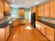 Spacious kitchen with wood cabinets, black appliances, granite countertops, and hardwood floors at 10940 Wild Dove Ln, Charlotte, NC 28277