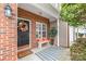 Cozy front porch featuring a brick facade, decorative wreath, and a striped rug over the concrete at 130 Clydesdale Ct, Matthews, NC 28104