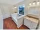 Bathroom featuring double sinks, a soaking tub under a window, and wood-look flooring at 1400 Wessex Ct, Monroe, NC 28110