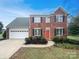 Charming two-story brick home with a red door, black shutters, and well-manicured landscaping at 1400 Wessex Ct, Monroe, NC 28110