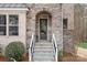 Close-up of the stone-arched front entrance with a decorative door and manicured landscaping at 147 Belfry Loop, Mooresville, NC 28117