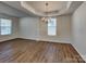 Elegant dining room featuring a decorative chandelier and tray ceiling over beautiful wood floors at 242 Elrosa Rd, Mooresville, NC 28115