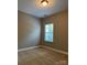 A simple bedroom with a neutral carpet, a window, and plain walls at 2608 Glyncastle Way, Gastonia, NC 28056