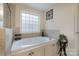 Elegant bathroom featuring a large soaking tub with tile surround and a bright window at 303 Ridge Reserve Dr # 29, Clover, SC 29710