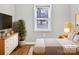 Cozy bedroom with hardwood floors, a comfortable bed, a dresser, and a large window at 325 Oregon St, Charlotte, NC 28208