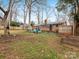 Wide shot of home's backyard with a fire pit, chairs, brick home, and mature trees at 3350 Bonneville Dr, Charlotte, NC 28205