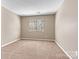 A well-lit bedroom with neutral walls, carpeted floor, and a large window with blinds offering natural light at 4139 N Course Dr, Charlotte, NC 28277