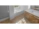 Bathroom featuring a garden tub, single sink vanity, and glass enclosed shower at 6318 Pink Dogwood Ln, Charlotte, NC 28262