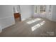 Sunlit living room featuring neutral carpet and white walls complemented by natural light streaming through large windows at 6318 Pink Dogwood Ln, Charlotte, NC 28262