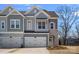Charming home featuring a stone archway, attached two-car garage, and manicured landscaping at 8233 Houser St, Cornelius, NC 28031