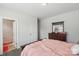 Bedroom with light pink bedspread, wooden dresser with mirror, and view into the ensuite bathroom at 8638 Raven Top Dr, Mint Hill, NC 28227