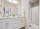 Modern bathroom with double sinks, white cabinets, a large mirror, and a shower with a patterned curtain at 924 Stebbins Dr, Fort Mill, SC 29715