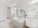 Bright bathroom with soaking tub, walk-in shower, double vanity with white cabinets, and neutral tile at 924 Stebbins Dr, Fort Mill, SC 29715