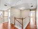 Upstairs hallway with hardwood floors, white railings, and doors leading to various rooms in the house at 10615 Persimmon Creek Dr, Mint Hill, NC 28227