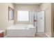 Bright bathroom featuring a soaking tub, glass-enclosed shower, and a window providing natural light at 10615 Persimmon Creek Dr, Mint Hill, NC 28227