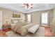 Bright main bedroom featuring a tray ceiling, ceiling fan, and neutral decor with light-colored walls and carpet at 10615 Persimmon Creek Dr, Mint Hill, NC 28227