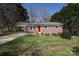 Charming brick home featuring a vibrant red door and a covered carport at 107 Stanford Dr, Stanley, NC 28164