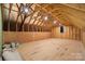 Unfinished attic space with exposed wood beams and a window providing natural light at 13101 Cozy Ct, Charlotte, NC 28215