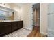 A modern bathroom featuring a double sink vanity, a large mirror, and an open walk-in closet at 13101 Cozy Ct, Charlotte, NC 28215