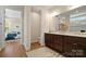 Bathroom with double sinks, wood cabinets and a walk-in shower; bedroom access is visible in the background at 13101 Cozy Ct, Charlotte, NC 28215