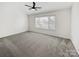Spacious bedroom featuring neutral carpet, a ceiling fan, and a large double window at 13424 Kibworth Ln, Charlotte, NC 28273